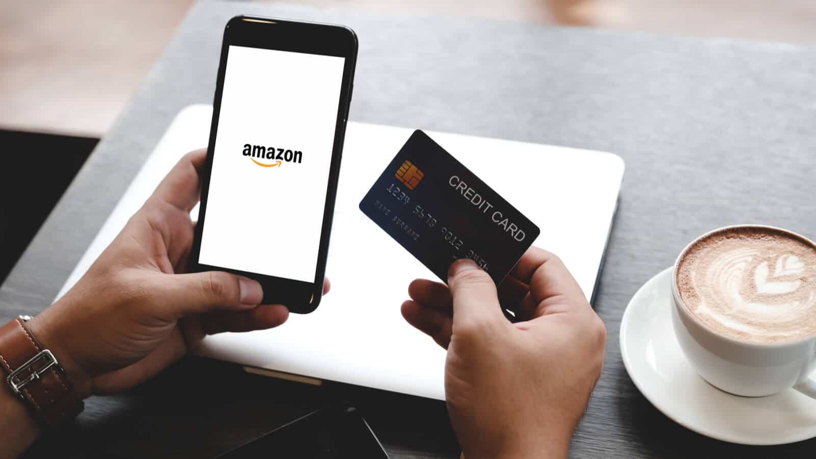 Mann an Smartphone, auf dem Amazon lädt, hat Kreditkarte in der Hand, um einen Black Friday und Cyber Monday Deal zu ergattern