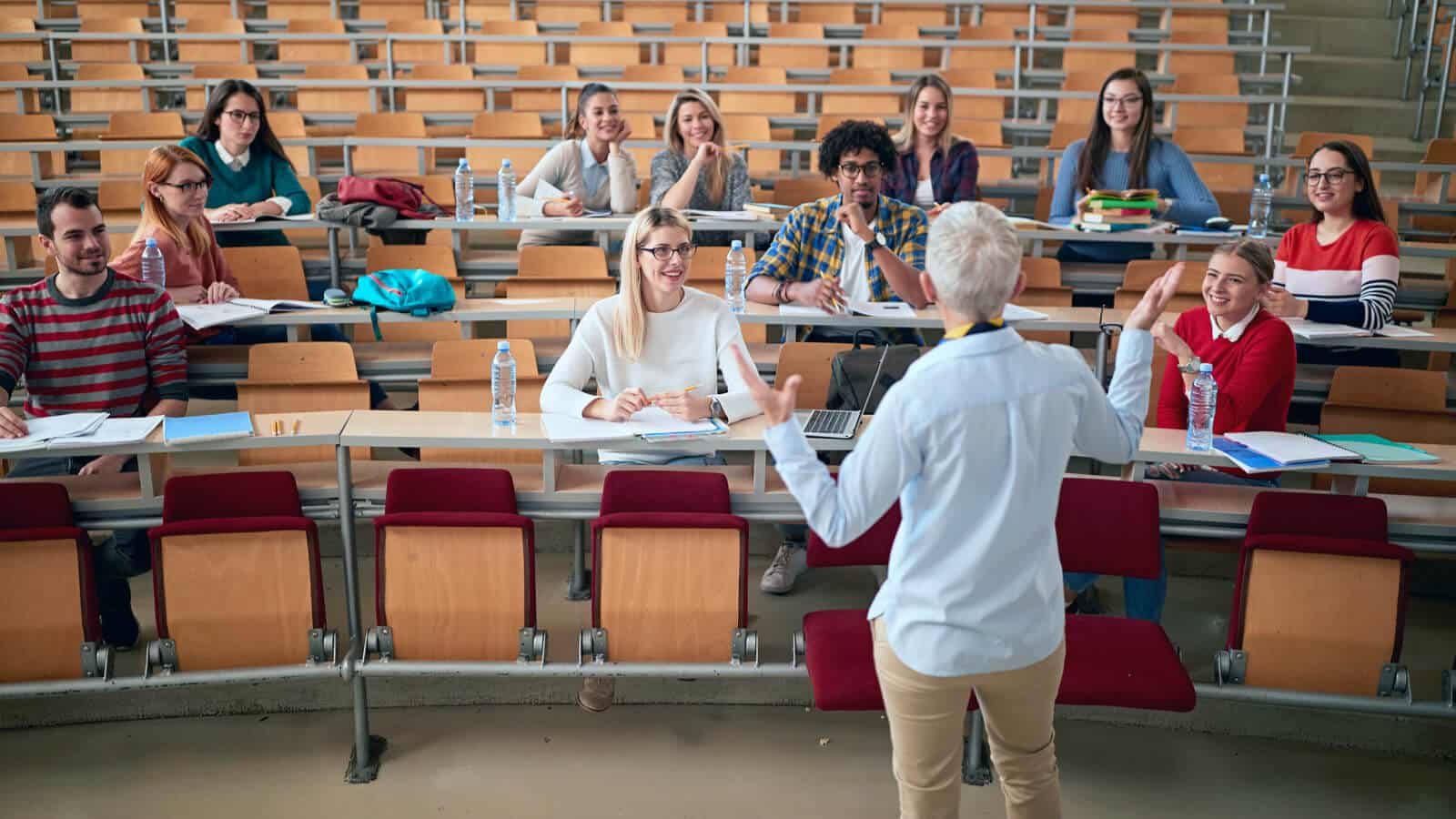 Eine Dozentin doziert vor einer Gruppe Studierenden im Vorlesungsraum.