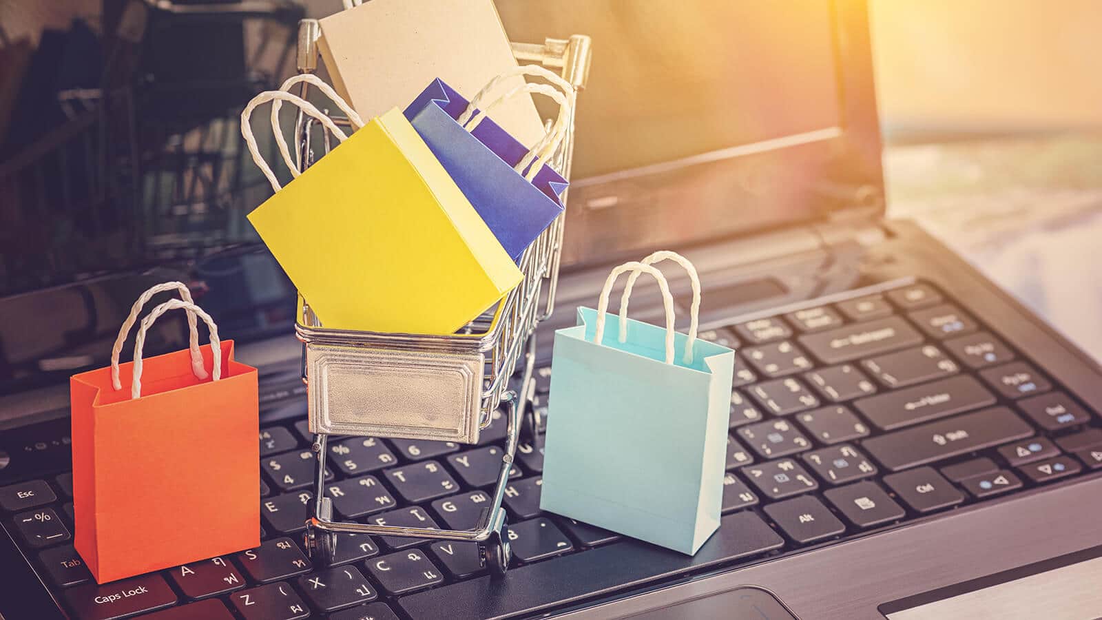 Laptop mit Einkaufstüten als Zeichen fürs E-Commerce Weihnachtsgeschäft