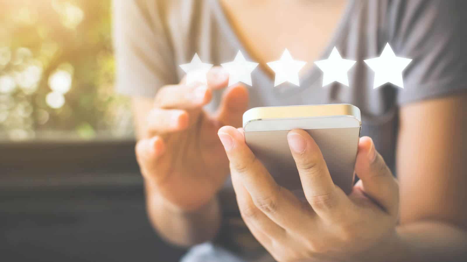 Frau am Smartphone gibt einem Unternehmen auf Google My Business eine 5-Sterne Bewertung.