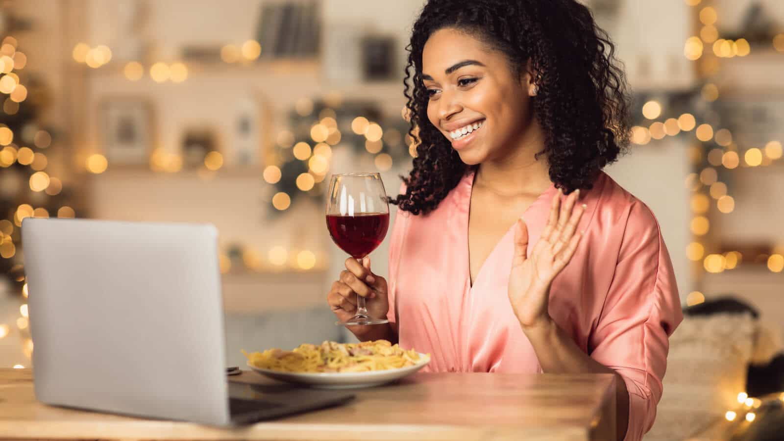 Eine Frau nimmt an einem virtuellen Event teil und isst Abendessen am Laptop.