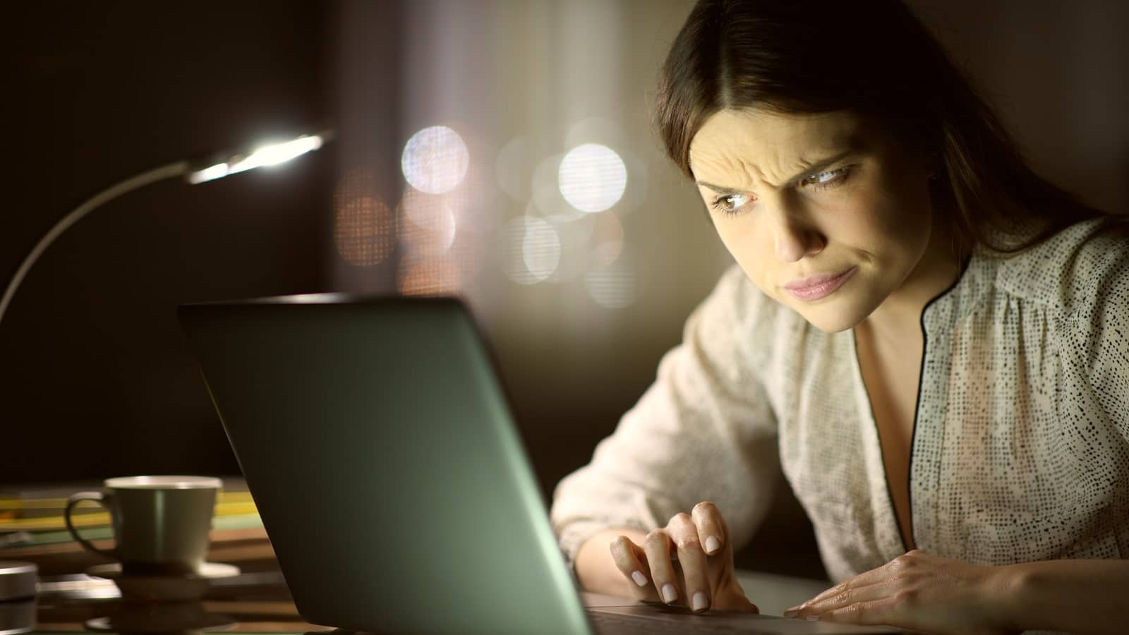 Eine Frau sitzt vor dem Laptop und starrt ihn verdächtig an.