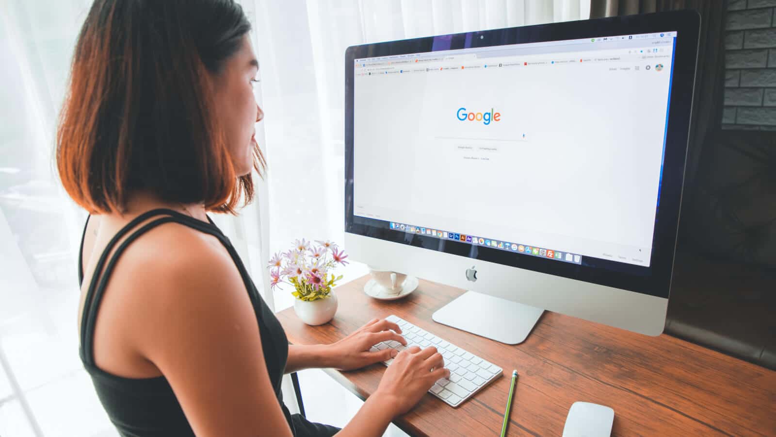 Eine junge Frau am Mac Computer tätigt eine Google Suche, bei denen SEA eine wichtige Rolle spielt und Agenturen helfen können