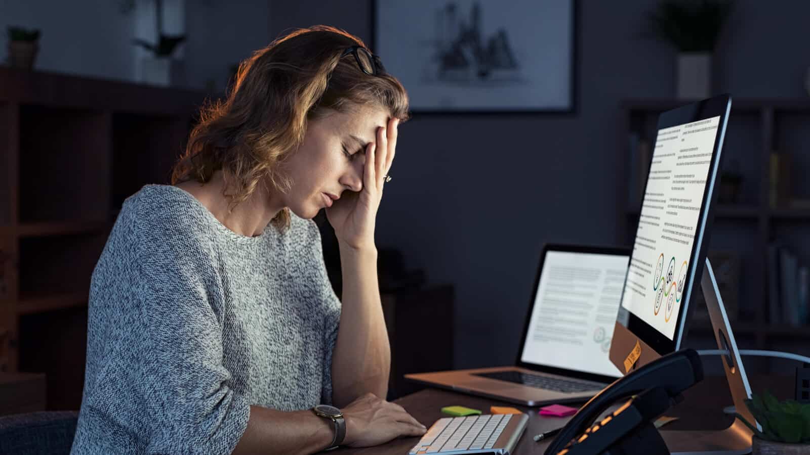 Eine Frau ist müde und gestresst vor dem Computer, sie leidet an einem Burnout