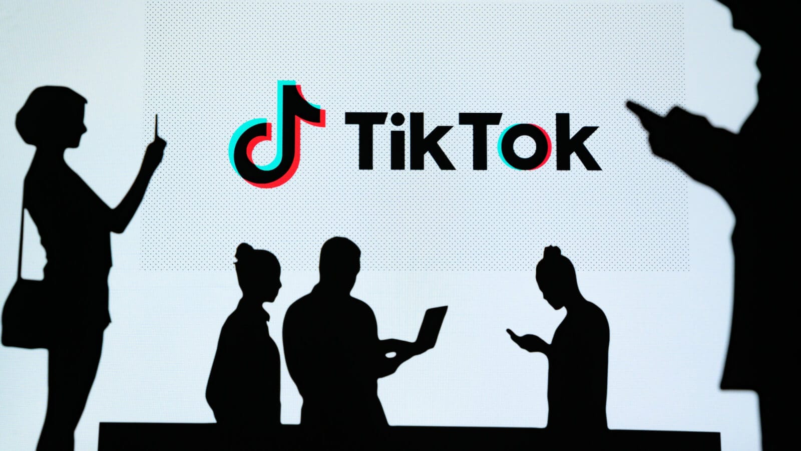 Personen vor dem TikTok-Logo am Laptop und Handy.