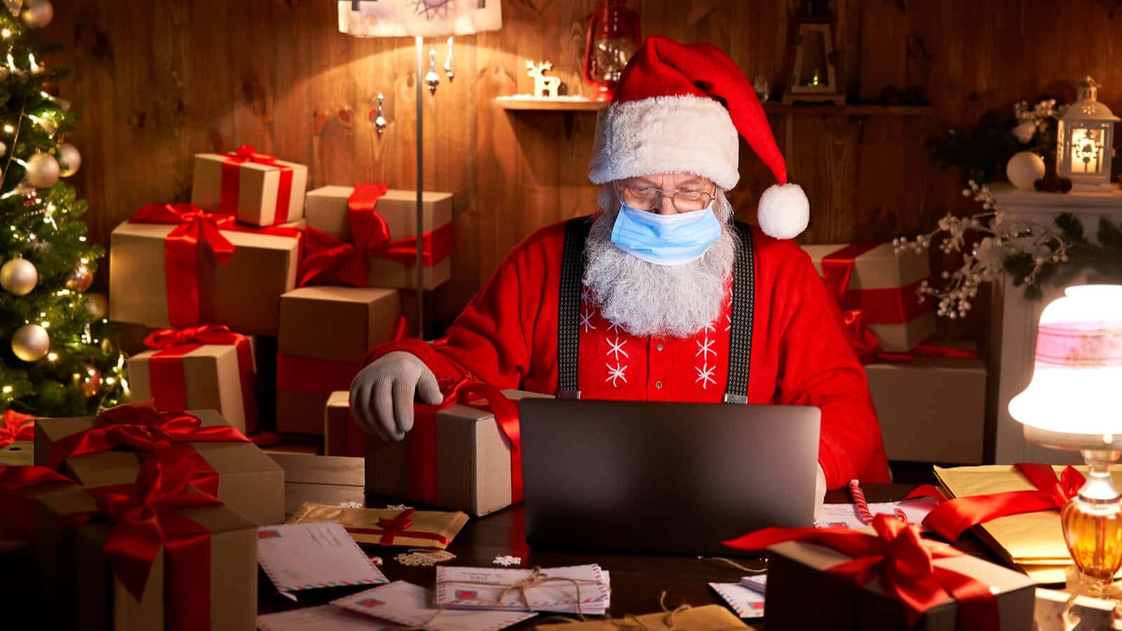 Weihnachtsmann mit Gesichtsmaske prüft einen Weihnachtsgruss via QR Code