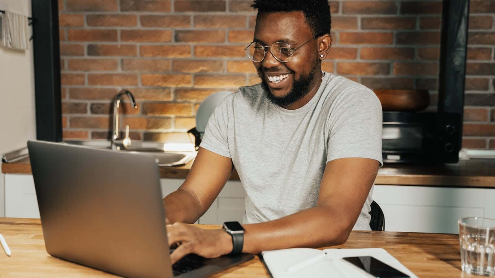 Ein Mann sitzt am Laptop und lacht.