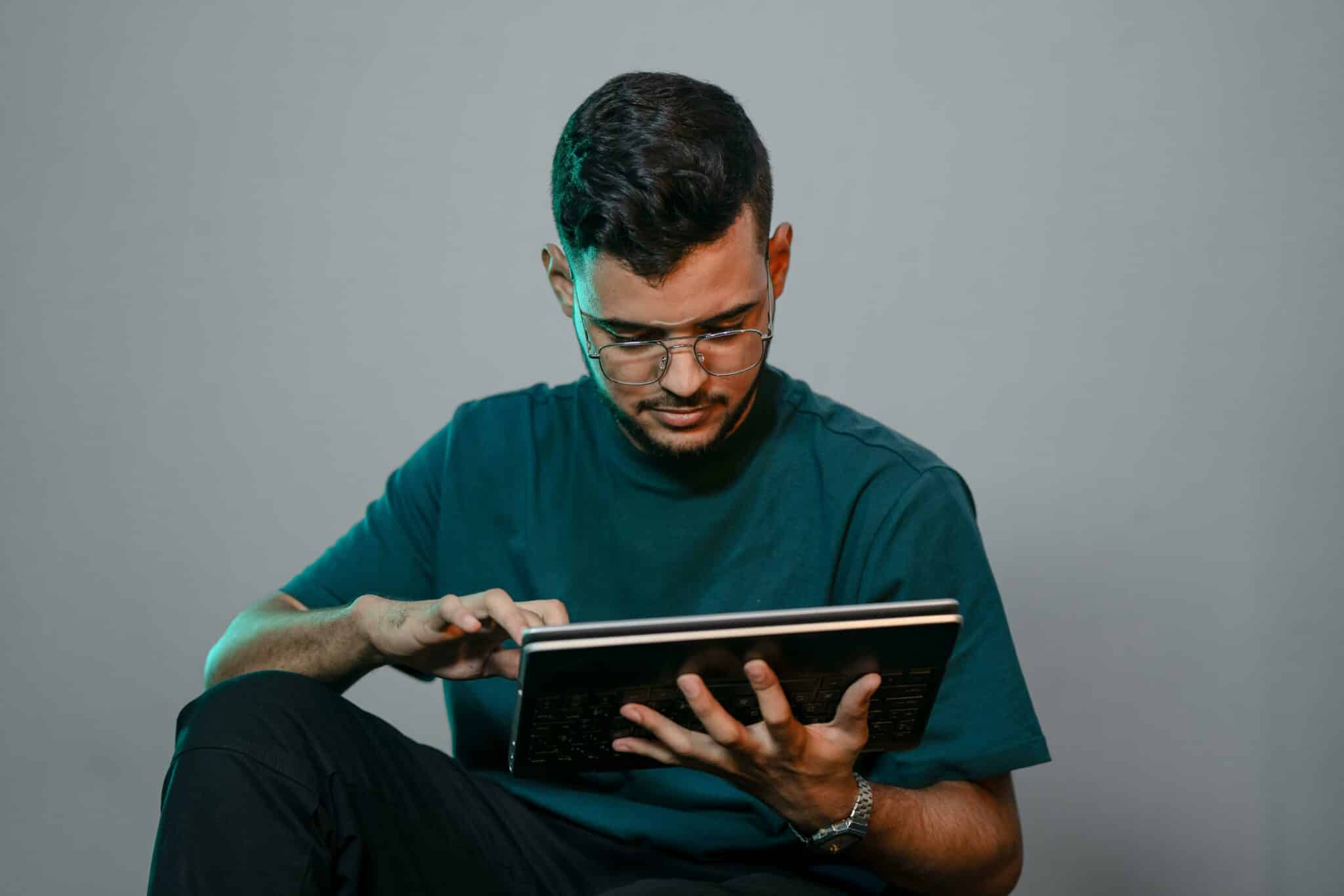 Ein Mann im dunkelgrünen T-Shirt benutzt ein Tablet.